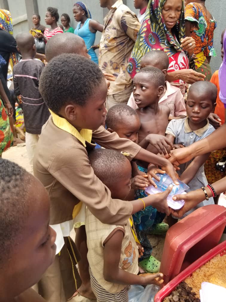 Homeless individuals, including children, receiving essential food items from OWENO Foundation